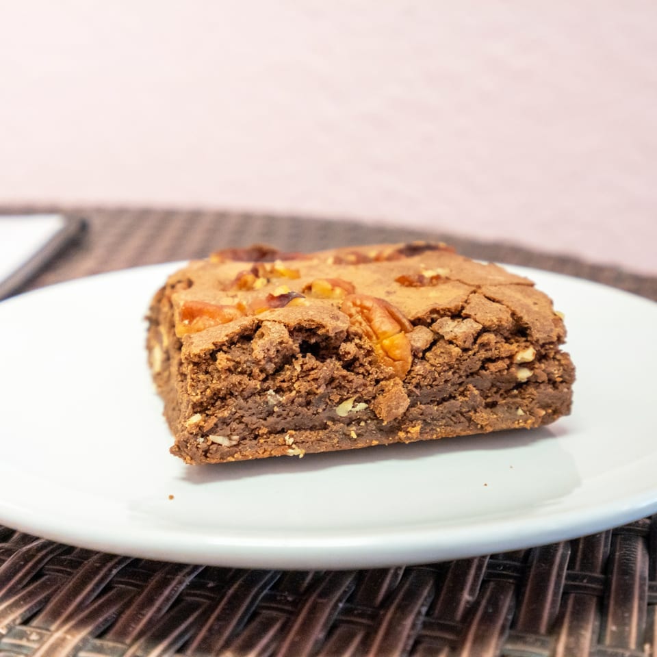Nut-topped brownie on a white plate